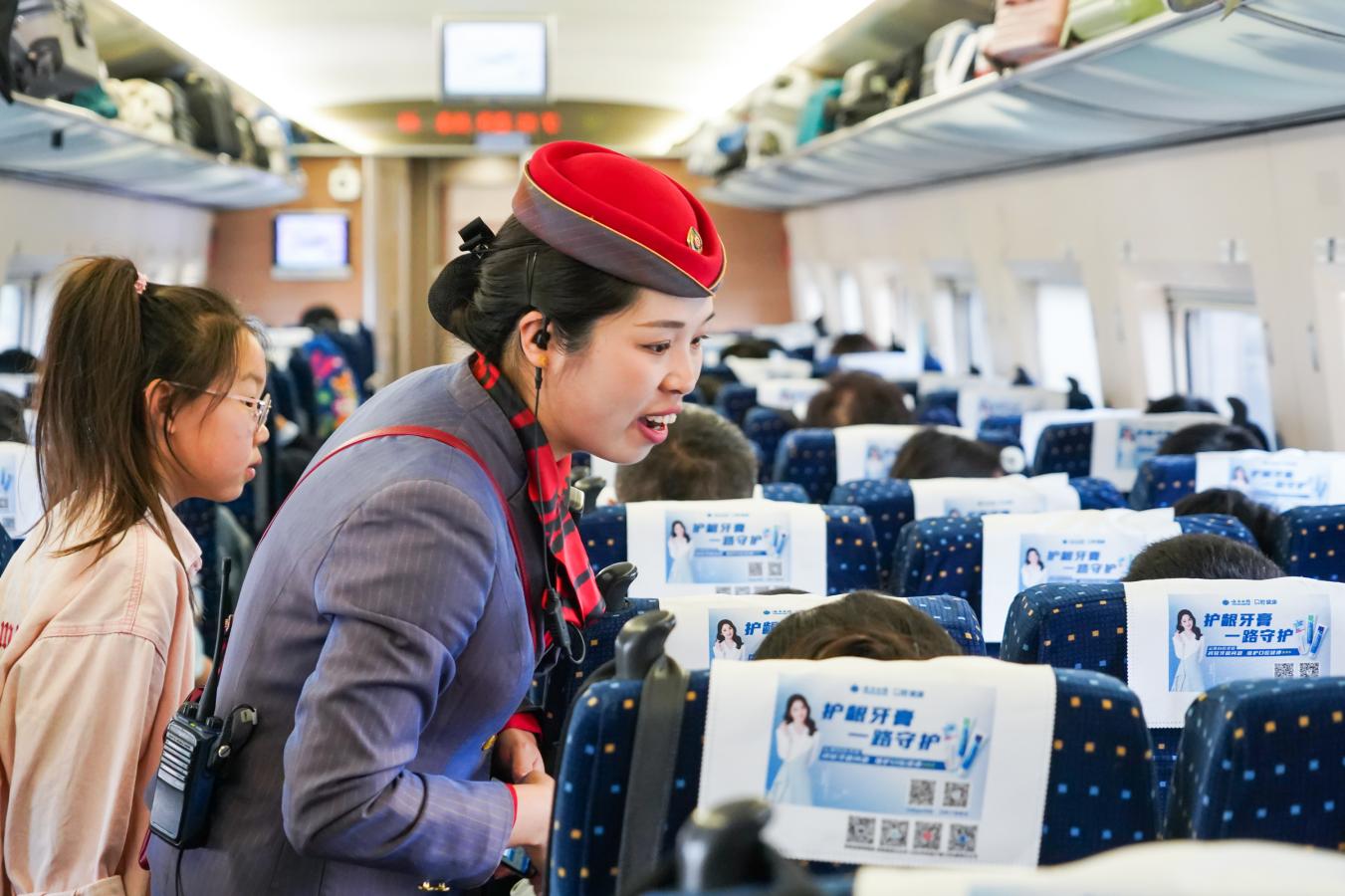 (10) 2024年5月1日，西安北至上海虹桥G1918次列车，西安客运段列车乘务员向重点旅客进行问询服务。（刘翔 摄）