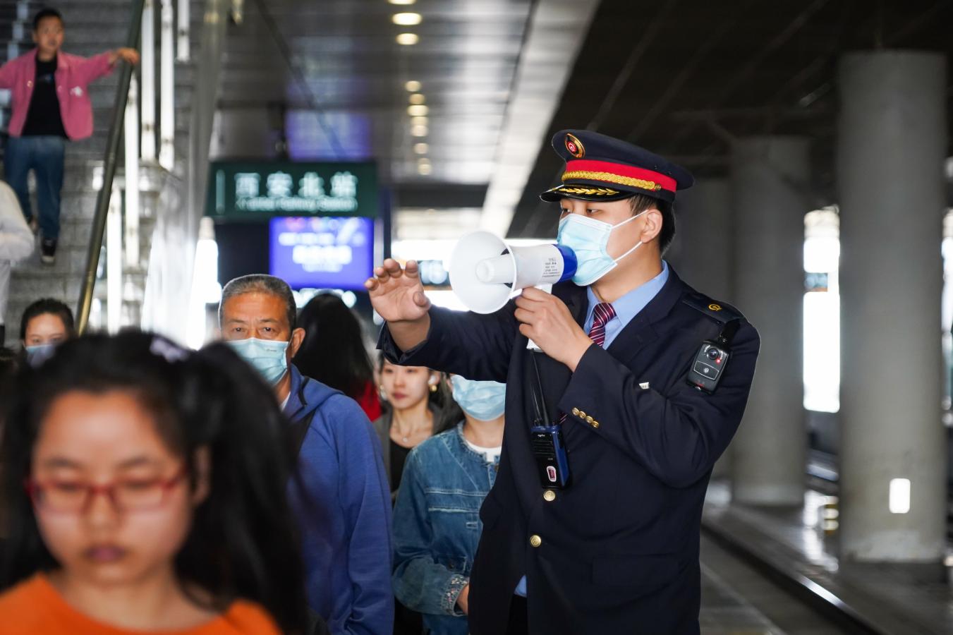(6) 2024年5月1日，西安北站，铁路客运工作人员在站台引导旅客有序排队登乘列车。（刘翔 摄）
