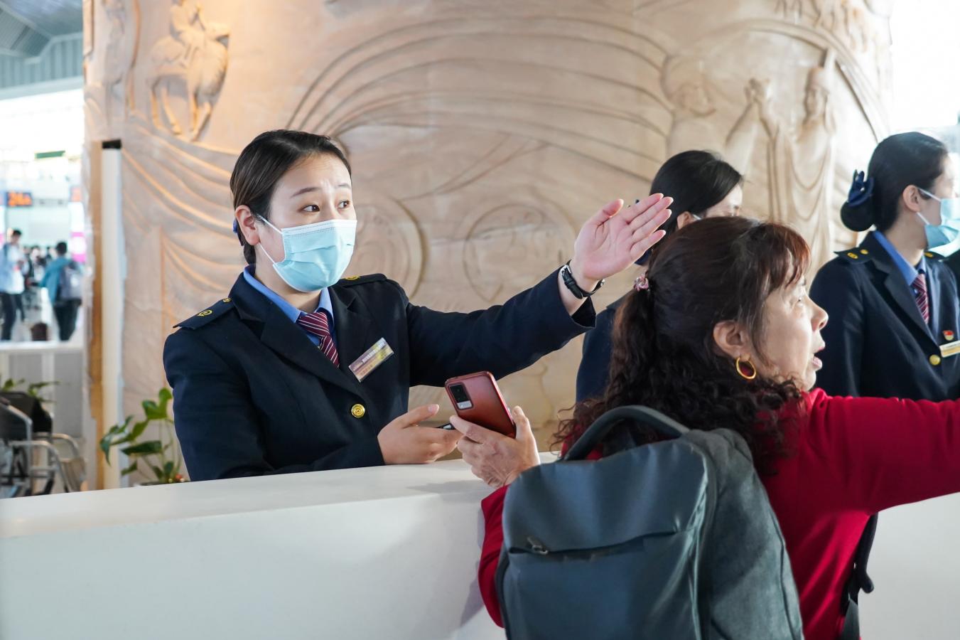 (5) 2024年5月1日，西安北站，铁路客运工作人员为旅客指引乘车路径。（刘翔 摄）