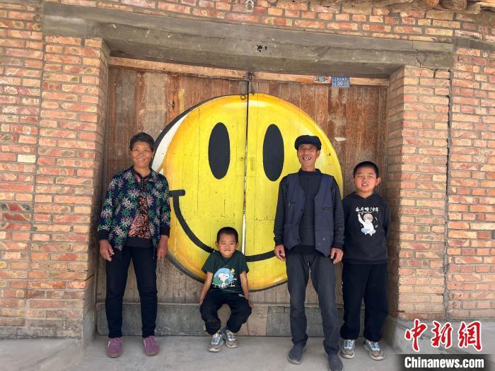 图为村民站在绘有“笑脸”的自家门口。王牧雨 摄

