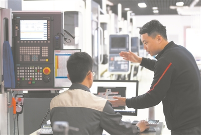 在广东省机械技师学院数控铣集训基地,老师(右)指导学生操作机床。新华社记者 邓华摄