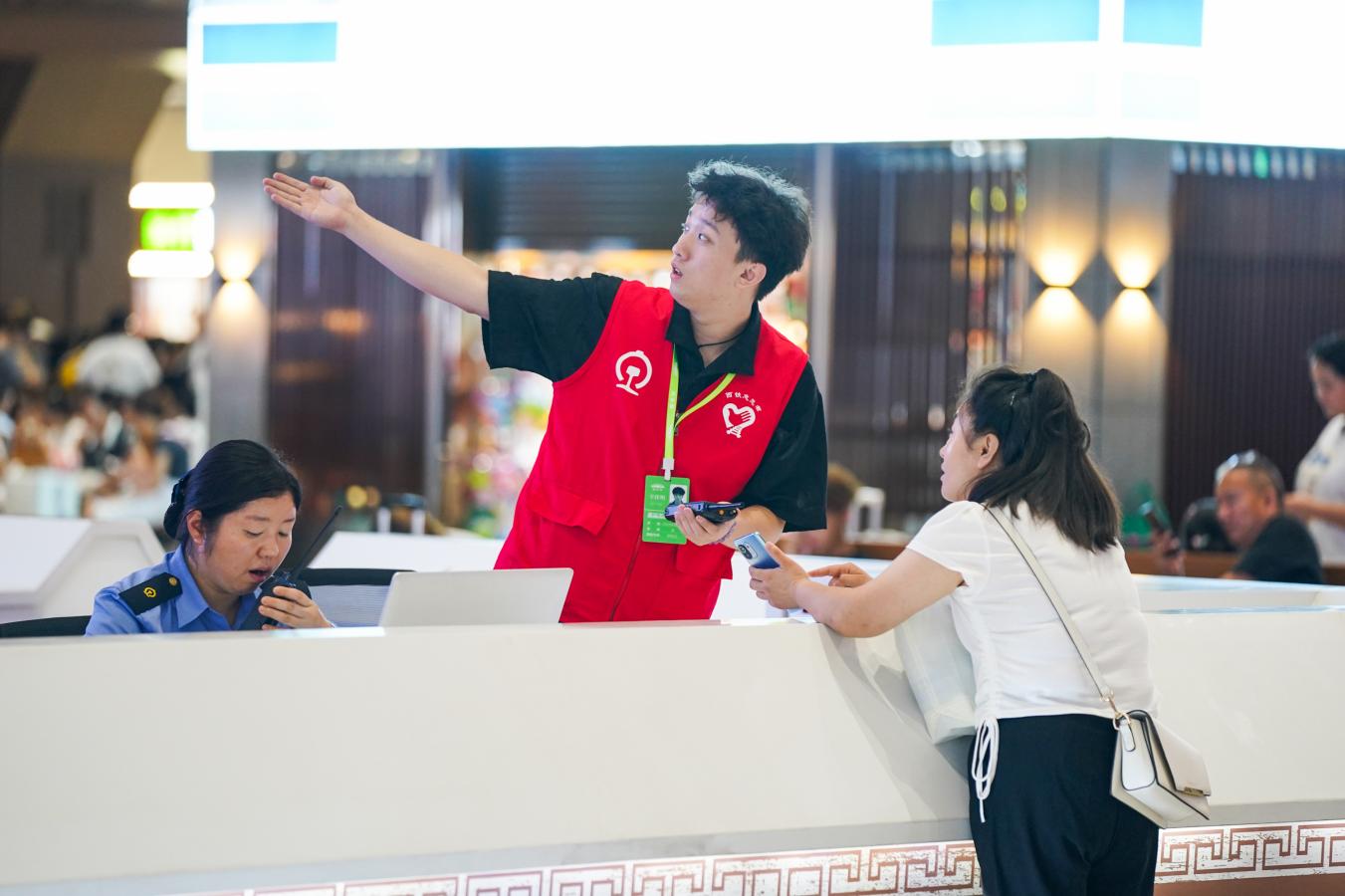 (5) 2024年8月5日，西安火车站，铁路工作人员为旅客提供乘车引导服务。（刘翔 摄）