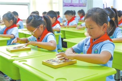 日照市新营小学学生在学习益智器具华容道“横刀立马”。本报记者 单艺伟 摄