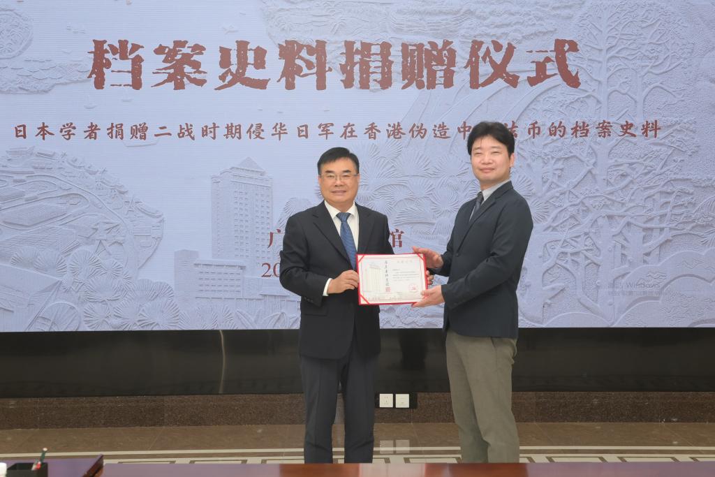 3月25日，广东省档案馆馆长李军晓（左）向捐赠者松野诚也（右）颁发档案捐赠证书。新华社发