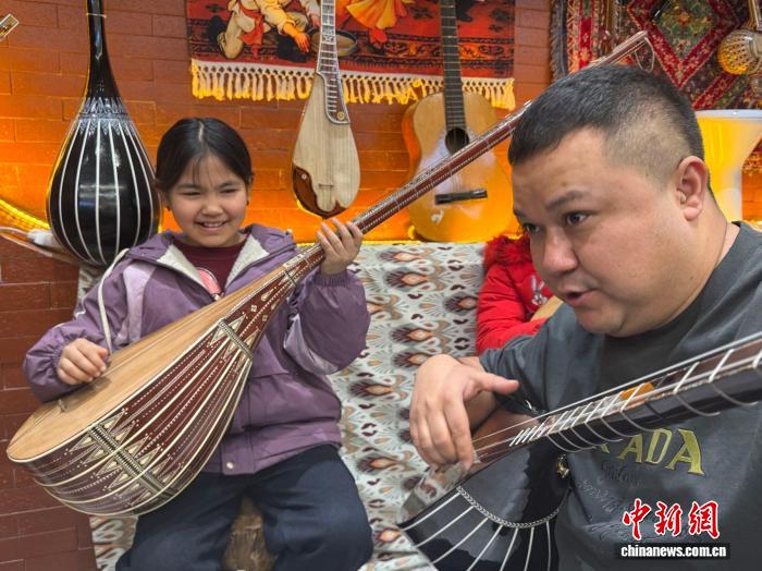 在新疆库车市“龟兹非遗工坊”里，学生们利用假期学习民族乐器。冀江彤 摄
