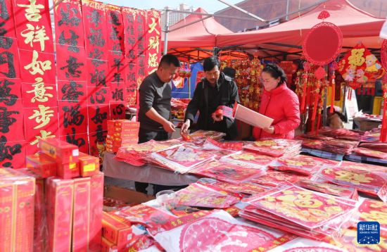 2月14日,人们在甘肃省定西市安定区年货市场选购春节饰品。