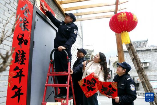 2月15日,河南省洛阳市汝阳县付店派出所民辅警给居民家贴春联挂灯笼,送去新春祝福。
