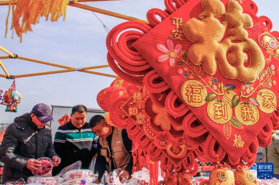 2月14日,人们在北京市平谷区的年货大集选购饰品。