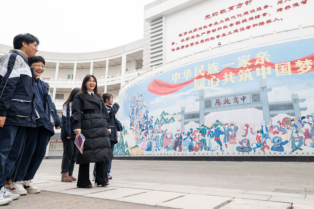 2月4日,在恩施土家族苗族自治州高级中学,张琼丽(右二)与学生从“中华民族一家亲 同心共筑中国梦”文化墙前走过。