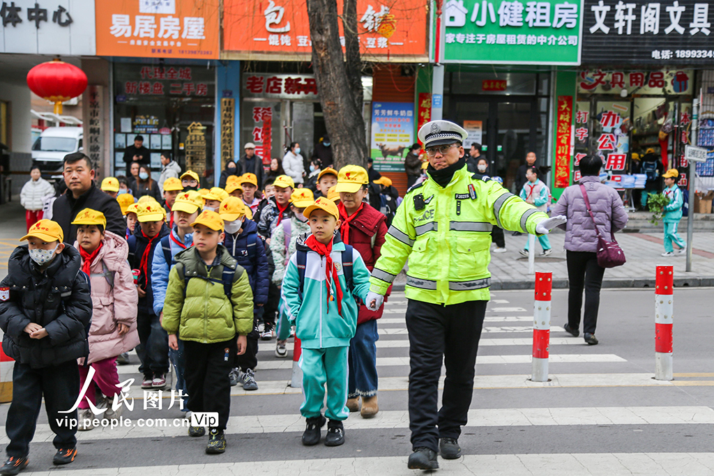 2026年3月2日，甘肃平凉市公安局崆峒分局交管大队执勤交警在学校门前的斑马线上，引导学生安全通过马路。郑兵摄（人民图片网）