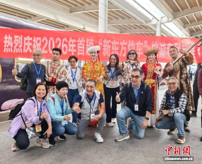 4月23日，乘坐2026年首趟“新东方快车”旅游专列的游客与新疆舞者在乌鲁木齐合影留念。　胡嘉琛 摄
