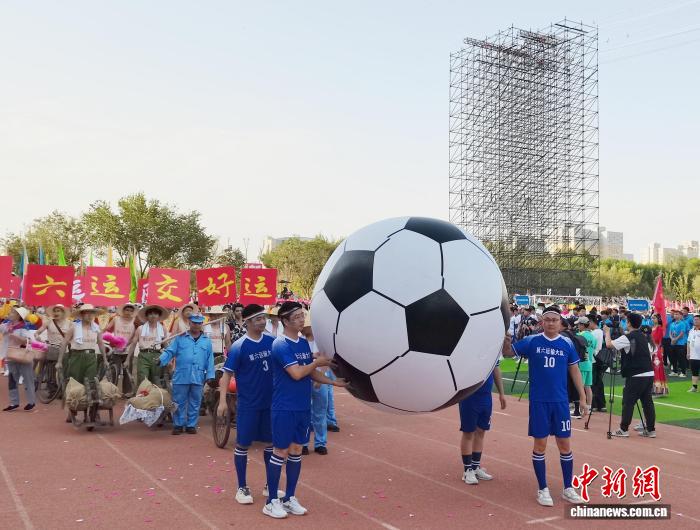 图为巡游方阵抬着巨型足球模型巡游。戚亚平 摄