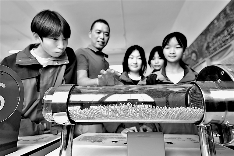 在湖北省襄阳市保康县过渡湾镇中心学校“流动科技馆”,教师指导学生体验科技展品“声驻波”。杨韬摄/光明图片
